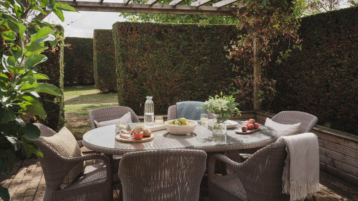 A yew-fringed patio welcomes alfresco dining under blue skies