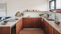 Local walnut wood cabinetry promises an inviting space for the chefs of the party...