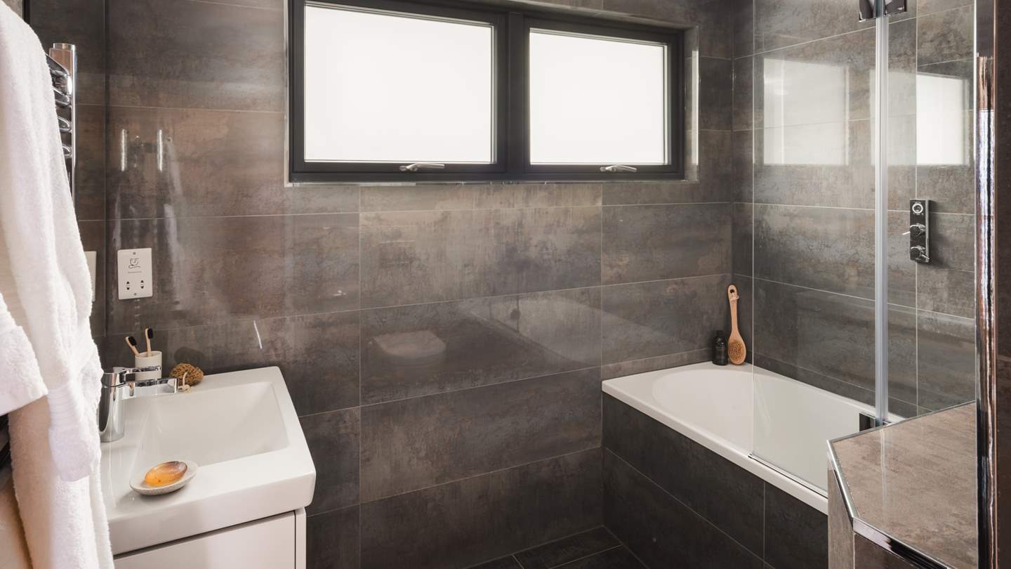 Charcoal tones reign in each of West Penthouse’s sleek bathroom spaces, the first with a bath and overhead shower
