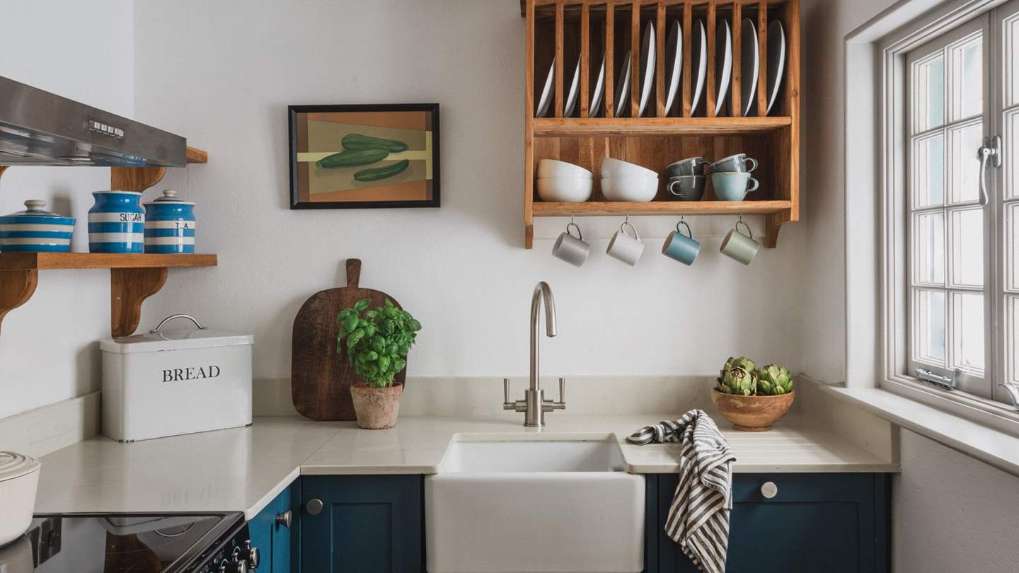 Drawing the eye, blue cabinets, open shelving, a butler sink and vintage finishings infuse period charm, cosily modernised with underfloor heating and modern appliances