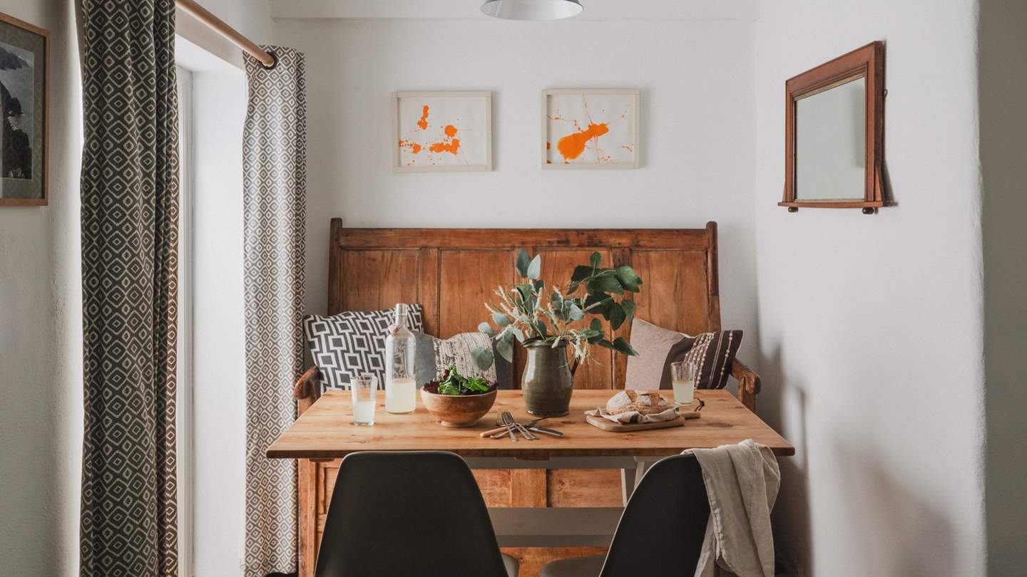 On the far side of the kitchen, a pine-scrubbed dining table, pew bench and Eames style chairs reside beside French doors