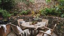 The pretty paved courtyard offers outdoor dining with a wooden table and chairs and Weber gas barbecue 