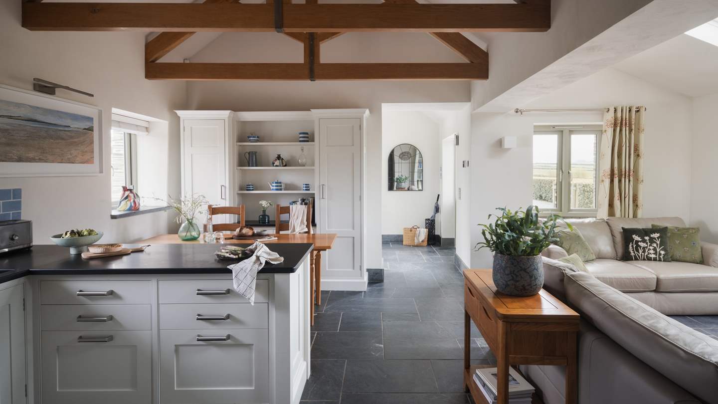 A timeless bespoke shaker-style kitchen, beautifully decorated in a charming hue of creamy white, boasts cool slate work surfaces and pale blue tiles